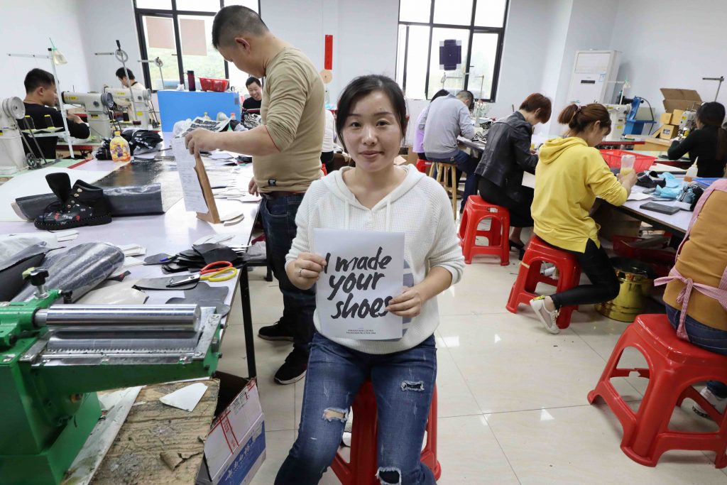 A shoe maker holding a sign saying "I made your shoes"